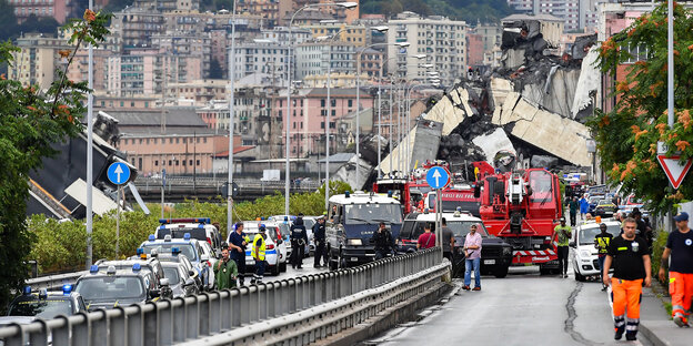 Feuerwehrwagen, Polizeiautos und Einsatzkräfte sind vor der teilweise eingestürzten Autobahnbrücke Ponte Morandi zu sehen Feuerwehrwagen, Polizeiautos und Einsatzkräfte sind vor der teilweise eingestürzten Autobahnbrücke Ponte Morandi zu sehen