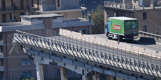 Ein grüner Lkw steht kurz vor der Kante der am Vortag eingestürzten Autobahnbrücke