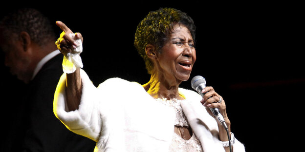 Aretha Franklin hält ein Mikrofon in der Hand und singt Aretha Franklin hält ein Mikrofon in der Hand und singt