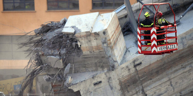 Feuerwehrleute entfernen Trümmer der teilweise eingestürzten Morandi Autobahnbrücke im italienischen Genua