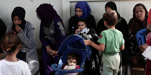 Frauen und Kinder sitzen im Flüchtlingscamp in Moria auf Lesbos, Griechenland Frauen und Kinder sitzen im Flüchtlingscamp in Moria auf Lesbos, Griechenland