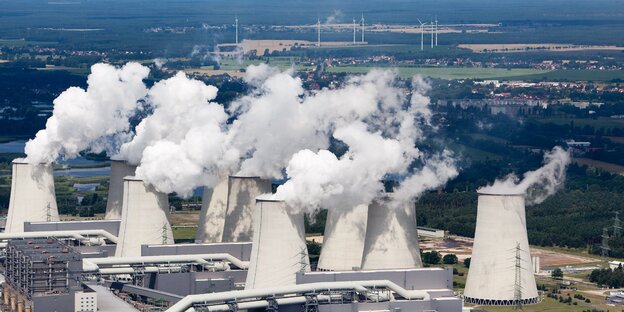 Dampfende Kühltürme, im Hintergrund einige Windkrafträder