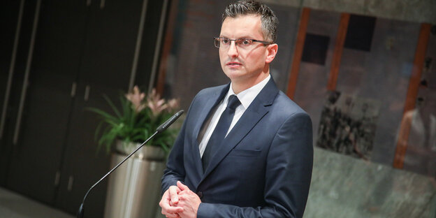 ein Mann mit verschränkten Händen vor einem Mikrofon ein Mann mit verschränkten Händen vor einem Mikrofon