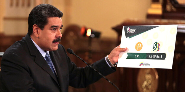 Venezuelas Präsdent Maduro hält ein Schild in der Hand, auf dem steht, dass ein Petro zukünftig 3 600 Bolivar kostet. Venezuelas Präsdent Maduro hält ein Schild in der Hand, auf dem steht, dass ein Petro zukünftig 3 600 Bolivar kostet.