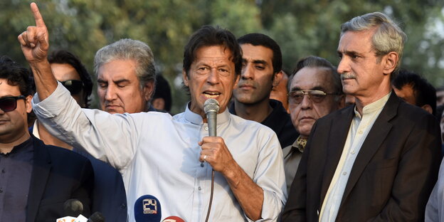 Imran Khan spricht in ein Mikro und hebt den einen Arm hoch Imran Khan spricht in ein Mikro und hebt den einen Arm hoch