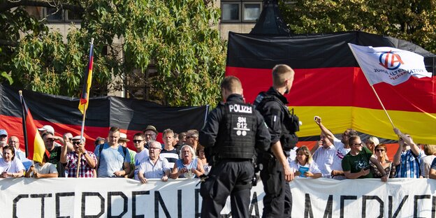 Demonstranten mit Transparent "Sterben, Frau Merkel", davor Polizisten Demonstranten mit Transparent "Sterben, Frau Merkel", davor Polizisten