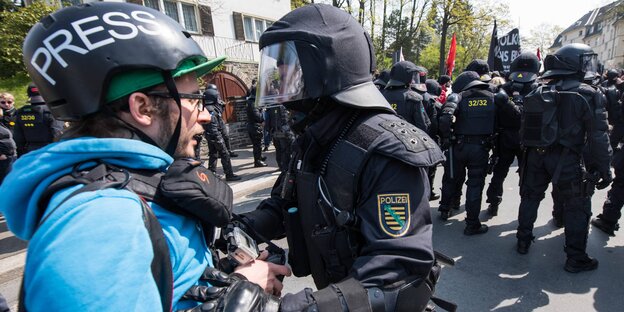 Ein Journalist und ein Polizist stehen nah beieinander Ein Journalist und ein Polizist stehen nah beieinander