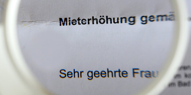 Blick durch Lupe auf einen Brief mit der Ankündigung einer Mieterhöhung Blick durch Lupe auf einen Brief mit der Ankündigung einer Mieterhöhung