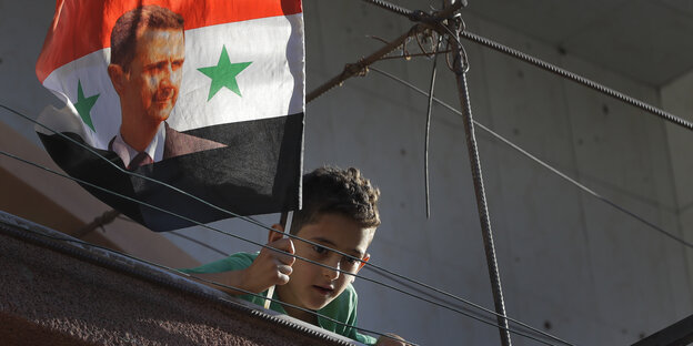Ein syrischer Junge schwenkt in Damaskus eine zerrissene Assad-Fahne Ein syrischer Junge schwenkt in Damaskus eine zerrissene Assad-Fahne