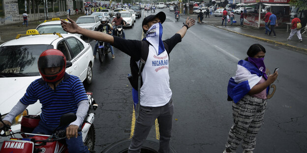 Ein Demonstrant steht mit ausgebreiteten Armen auf der Straße Ein Demonstrant steht mit ausgebreiteten Armen auf der Straße