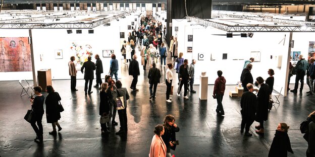 Eine Kunstausstellung von oben, mehrere Menschen laufen umher Eine Kunstausstellung von oben, mehrere Menschen laufen umher