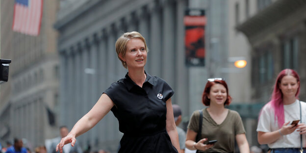 Cynthia Nixon läuft durch die Straßen, hinter ihr die US-Flagge und zwei Frauen Cynthia Nixon läuft durch die Straßen, hinter ihr die US-Flagge und zwei Frauen
