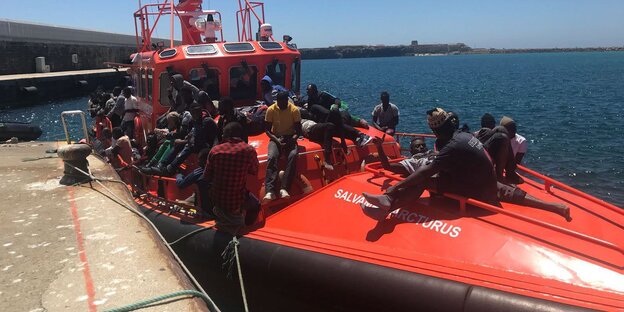 Rotes Boot liegt am Kai, viele Menschen ab Bord Rotes Boot liegt am Kai, viele Menschen ab Bord