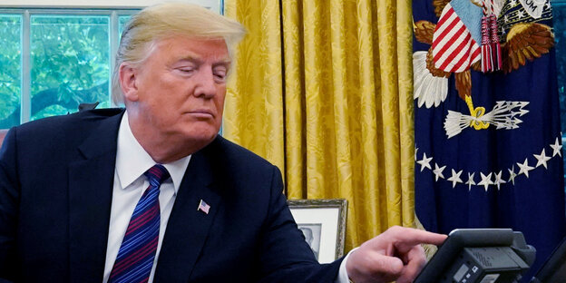 Trump bettätigt sein Telefon am Schreibtisch Trump bettätigt sein Telefon am Schreibtisch