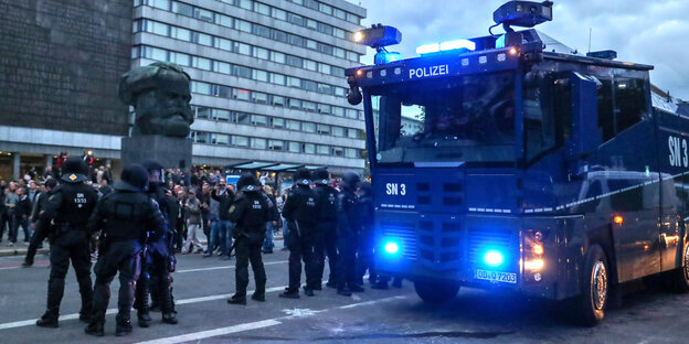 Polizisten mit Wasserwerfer Polizisten mit Wasserwerfer