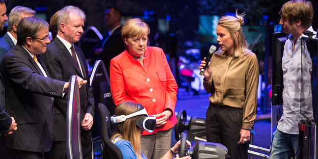 Merkel schaut einem Mädchen bei einem Videospiel zu Merkel schaut einem Mädchen bei einem Videospiel zu