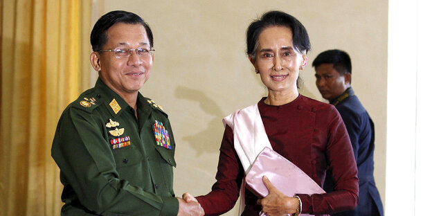 Min Aung Hlaing und Aung San Suu Kyi geben sich die Hand und schauen dabei in die Kamera Min Aung Hlaing und Aung San Suu Kyi geben sich die Hand und schauen dabei in die Kamera