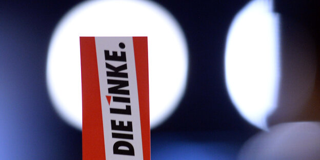 Vor einem Lichtkegel wird ein Zettel mit dem Aufschrift "Die Linke" hochgehalten Vor einem Lichtkegel wird ein Zettel mit dem Aufschrift "Die Linke" hochgehalten