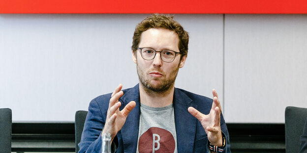 Jan Philipp Albrecht sitzt an einem Tisch und gestikuliert. Jan Philipp Albrecht sitzt an einem Tisch und gestikuliert.