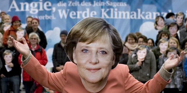 Aktivisten verkleidet als Angela Merkel vor dem Plakat mit der Aufschrift "Angie, werde Klimakanzlerin" Aktivisten verkleidet als Angela Merkel vor dem Plakat mit der Aufschrift "Angie, werde Klimakanzlerin"