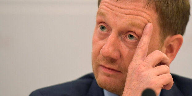 Kretschmer hält sich eine Hand an die Wange Kretschmer hält sich eine Hand an die Wange