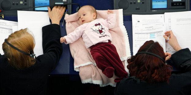 Im EU-Parlament liegt ein Baby zwischen zwei Frauen auf einem Tisch Im EU-Parlament liegt ein Baby zwischen zwei Frauen auf einem Tisch