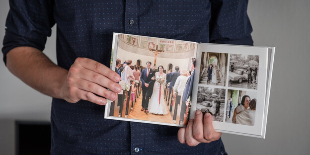 Ein Mann zeigt ein Fotobuch mit Fotos seiner Hochzeit. Die Braut war in Weiß Ein Mann zeigt ein Fotobuch mit Fotos seiner Hochzeit. Die Braut war in Weiß