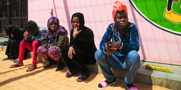 Afrikanische Migranten, u.a. aus Nigeria, sitzen im Hof eines Flüchtlingslagers in Tripolis (Libyen). Afrikanische Migranten, u.a. aus Nigeria, sitzen im Hof eines Flüchtlingslagers in Tripolis (Libyen).