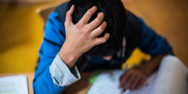 Ein Kind lernt, den Kopf in die Hand gestützt Ein Kind lernt, den Kopf in die Hand gestützt