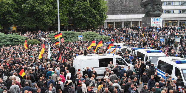 Menschen mit Deutschlandflaggen ziehen vor das Karl-Marx-Denkmal in Chemnitz Menschen mit Deutschlandflaggen ziehen vor das Karl-Marx-Denkmal in Chemnitz