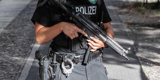 Eine Frau hält eine große Waffe vor ihrem Körper Eine Frau hält eine große Waffe vor ihrem Körper