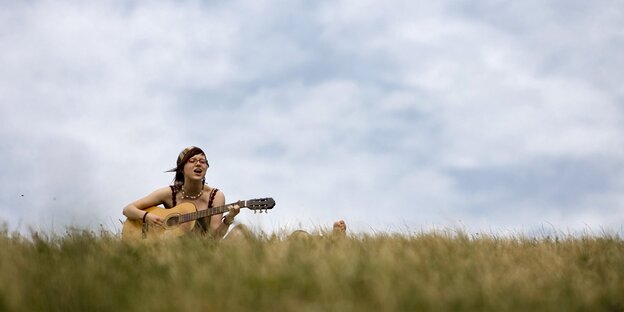 Eine Frau mit Gitarre in einer Wiese Eine Frau mit Gitarre in einer Wiese