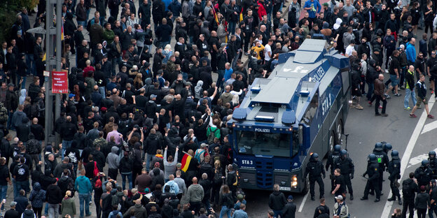 Teilnehmer der Demonstration von AfD und dem ausländerfeindlichen Bündnis Pegida, der sich auch die Teilnehmer der Kundgebung der rechtspopulistischen Bürgerbewegung Pro Chemnitz angeschlossen haben, stehen neben einem Wasserwerfer.