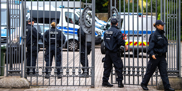 Fünf Polizisten stehen an einem eisernen Tor Fünf Polizisten stehen an einem eisernen Tor