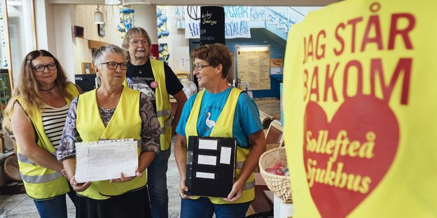 Ältere Menschen in einem Raum mit Protestplakat