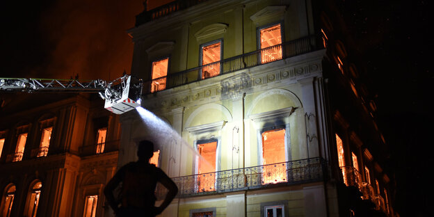 Ein brennendes Gebäude, davor ein Kran der Feuerwehr Ein brennendes Gebäude, davor ein Kran der Feuerwehr