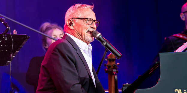 Liedermacher Konstantin Wecker sitzt bei einem Konzert an seinem Flügel und singt Liedermacher Konstantin Wecker sitzt bei einem Konzert an seinem Flügel und singt