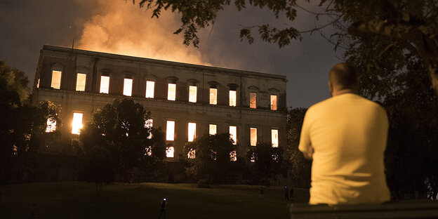 Ein Mann steht vor einem brennenden Gebäude Ein Mann steht vor einem brennenden Gebäude