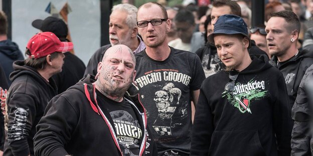 Mehrere radikale Männer, einer von ihnen schaut haßerfüllt in Richtung Kamera Mehrere radikale Männer, einer von ihnen schaut haßerfüllt in Richtung Kamera