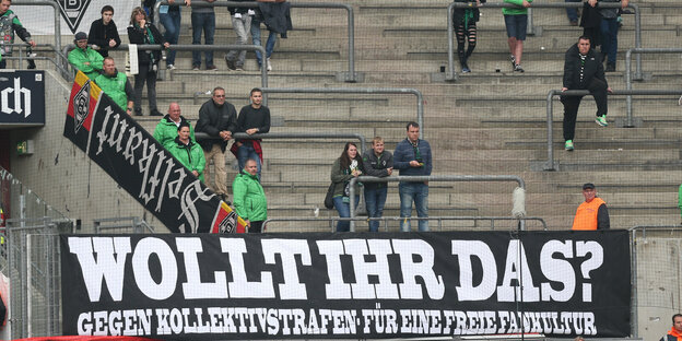 Eine fast leere Stehtribüne, vor der ein Spruchband hängt. Aufschrift: Wollt ihr das? Gegen Kollektivstrafen