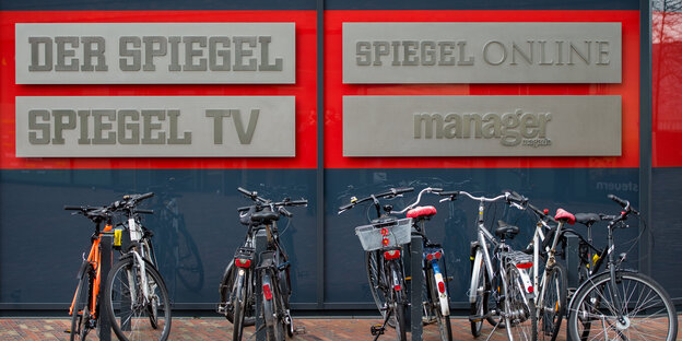 Fahrräder stehen an Fahrradständern. Dahinter die Schriftzüge. Der Spiegel, Spiegel TV, Spiegel Online und Manager Magazin Fahrräder stehen an Fahrradständern. Dahinter die Schriftzüge. Der Spiegel, Spiegel TV, Spiegel Online und Manager Magazin
