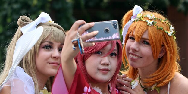 Drei Frauen in Mangakostümen machen ein Selfie Drei Frauen in Mangakostümen machen ein Selfie