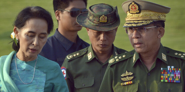 Myanmars Außenministerin Aung San Suu Kyi läuft neben zwei Militärs Myanmars Außenministerin Aung San Suu Kyi läuft neben zwei Militärs