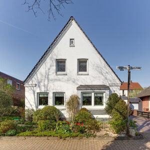 Frontalansicht eines weißen zweigeschossigen Hauses mit Giebel Frontalansicht eines weißen zweigeschossigen Hauses mit Giebel
