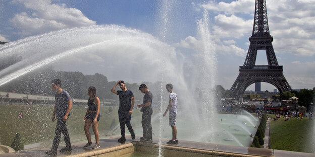 Junge Leute kühlen sich an einem Springbrunnen ab Junge Leute kühlen sich an einem Springbrunnen ab
