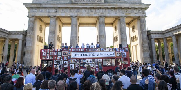 Ein roter Bus, mit gerahmten Fotos behangen, steht vor dem Brandenburger Tor Ein roter Bus, mit gerahmten Fotos behangen, steht vor dem Brandenburger Tor