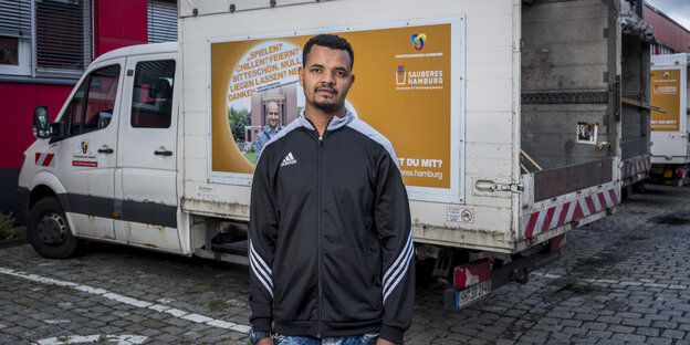 Abadir M. steht vor einem Auto der Hamburger Stadtreinigung.