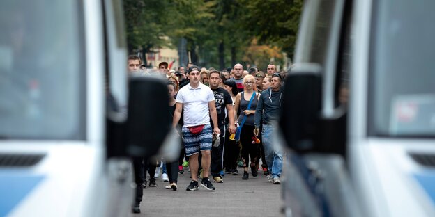 Zwei Polizeiautos im Vordergrund, dahinter sieht man den Trauermarsch Zwei Polizeiautos im Vordergrund, dahinter sieht man den Trauermarsch