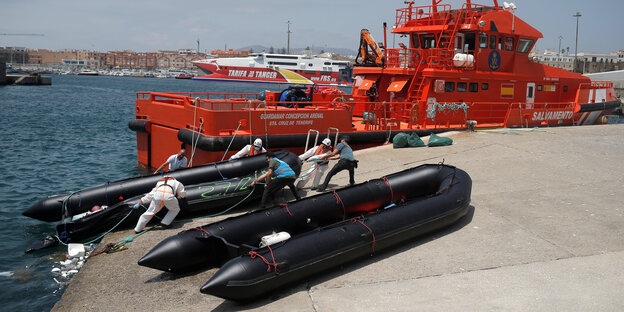 Zwei schwarze Schlauchboote vor einem orange farbenen Grenzschutzschiff Zwei schwarze Schlauchboote vor einem orange farbenen Grenzschutzschiff