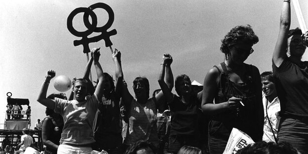 Ein schwarz-weiß Bild zeigt eine Demonstration, Frauen halten ein Plakat mit dem Frauensymbol hoch Ein schwarz-weiß Bild zeigt eine Demonstration, Frauen halten ein Plakat mit dem Frauensymbol hoch